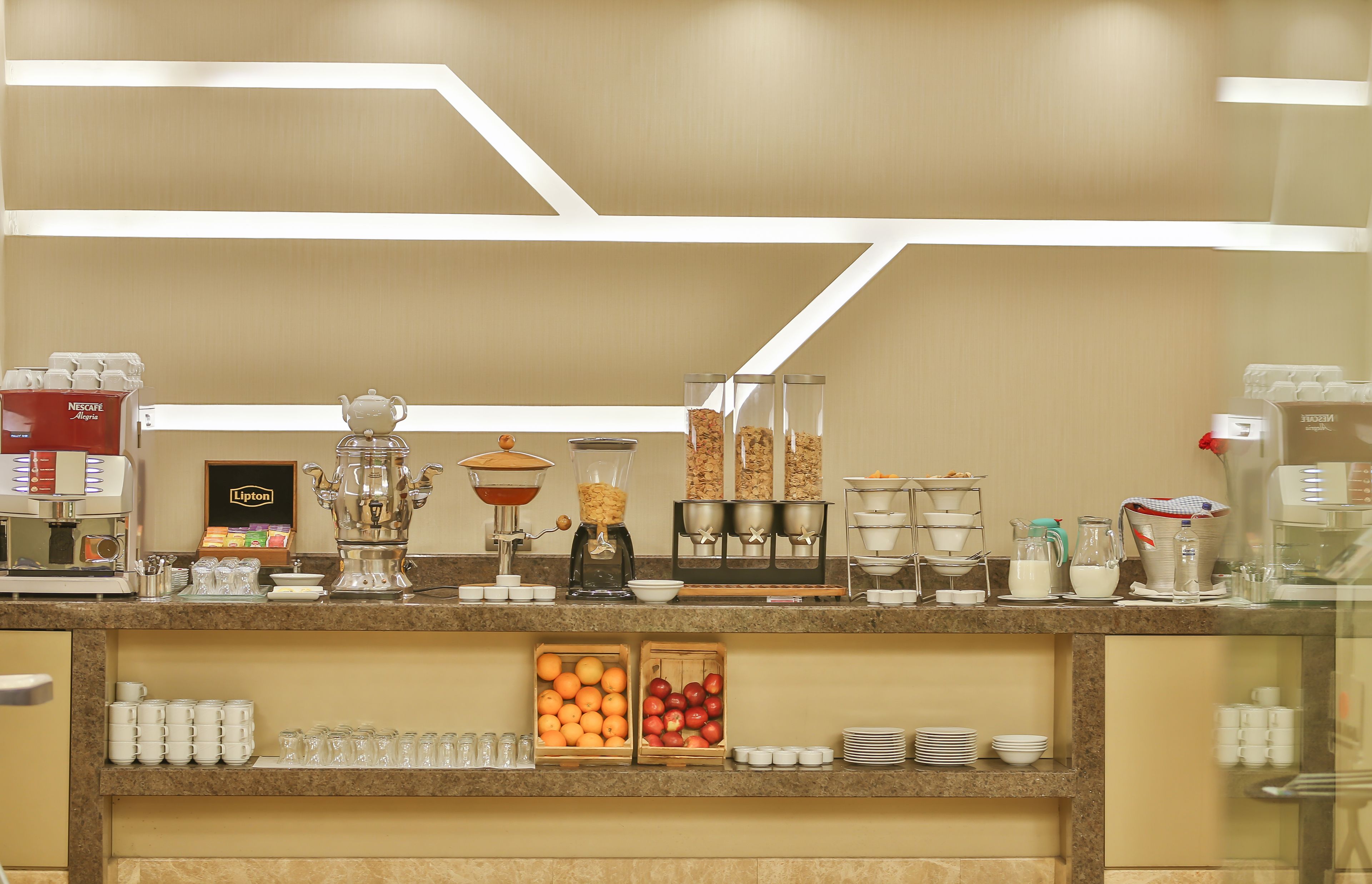 A breakfast bar with coffee machines, a tea station, and a fruit display.