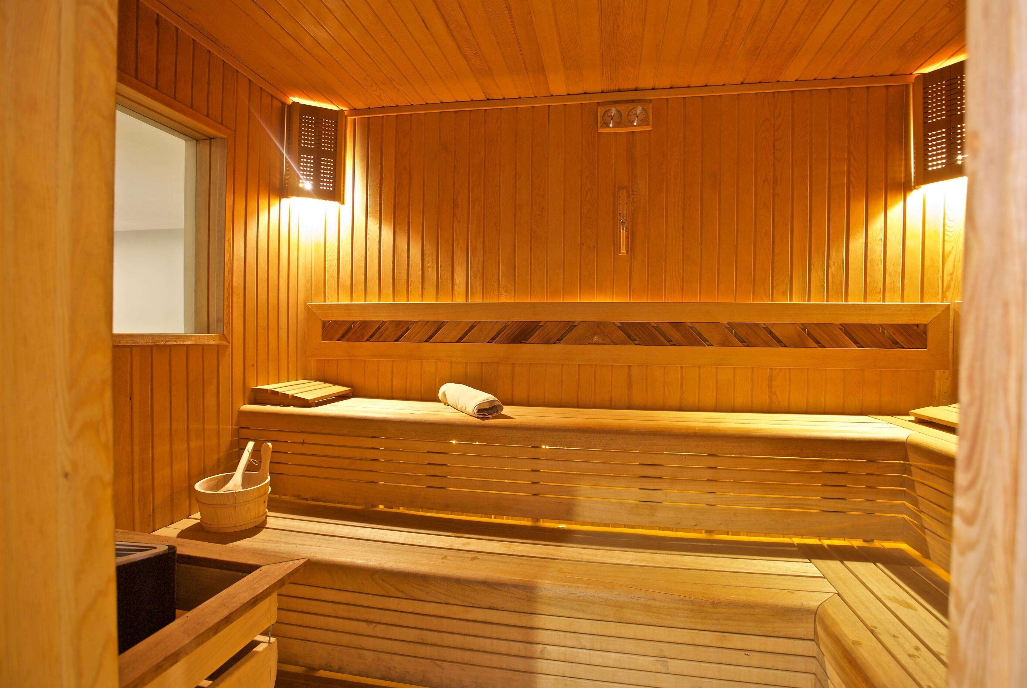 A wooden sauna with benches, a bucket, and a towel.