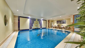 An indoor swimming pool with a tiled wall and a lounge area with chairs and a table. - Ramada by Wyndham Istanbul Taksim (Istanbul)