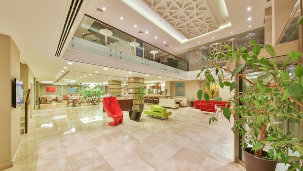 A spacious lobby with a high ceiling, a glass railing balcony, and a large potted plant. - Ramada by Wyndham Istanbul Taksim (Istanbul)