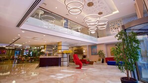 A spacious lobby with a modern design, featuring a reception desk, seating areas, and a large glass window. - Ramada by Wyndham Istanbul Taksim (Istanbul)