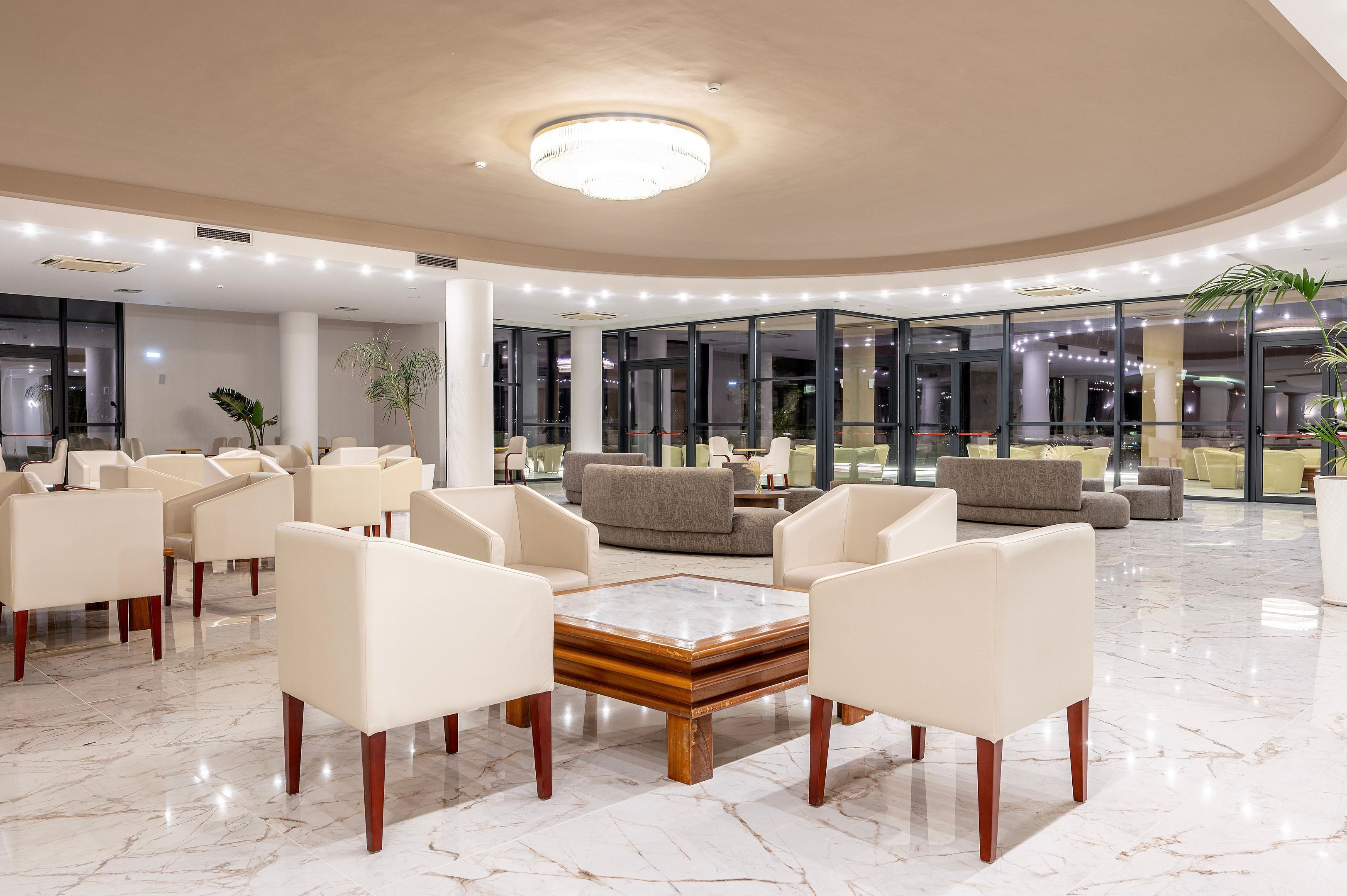 A spacious lobby with a marble floor, modern furniture, and large windows offering views of the city.