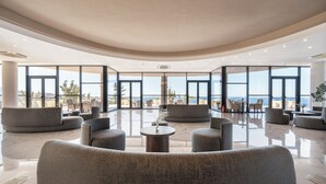 A spacious lobby with a curved ceiling, large windows offering a view of the sea, and modern seating arrangements. - Athina Palace Resort & Spa (Malevizi)