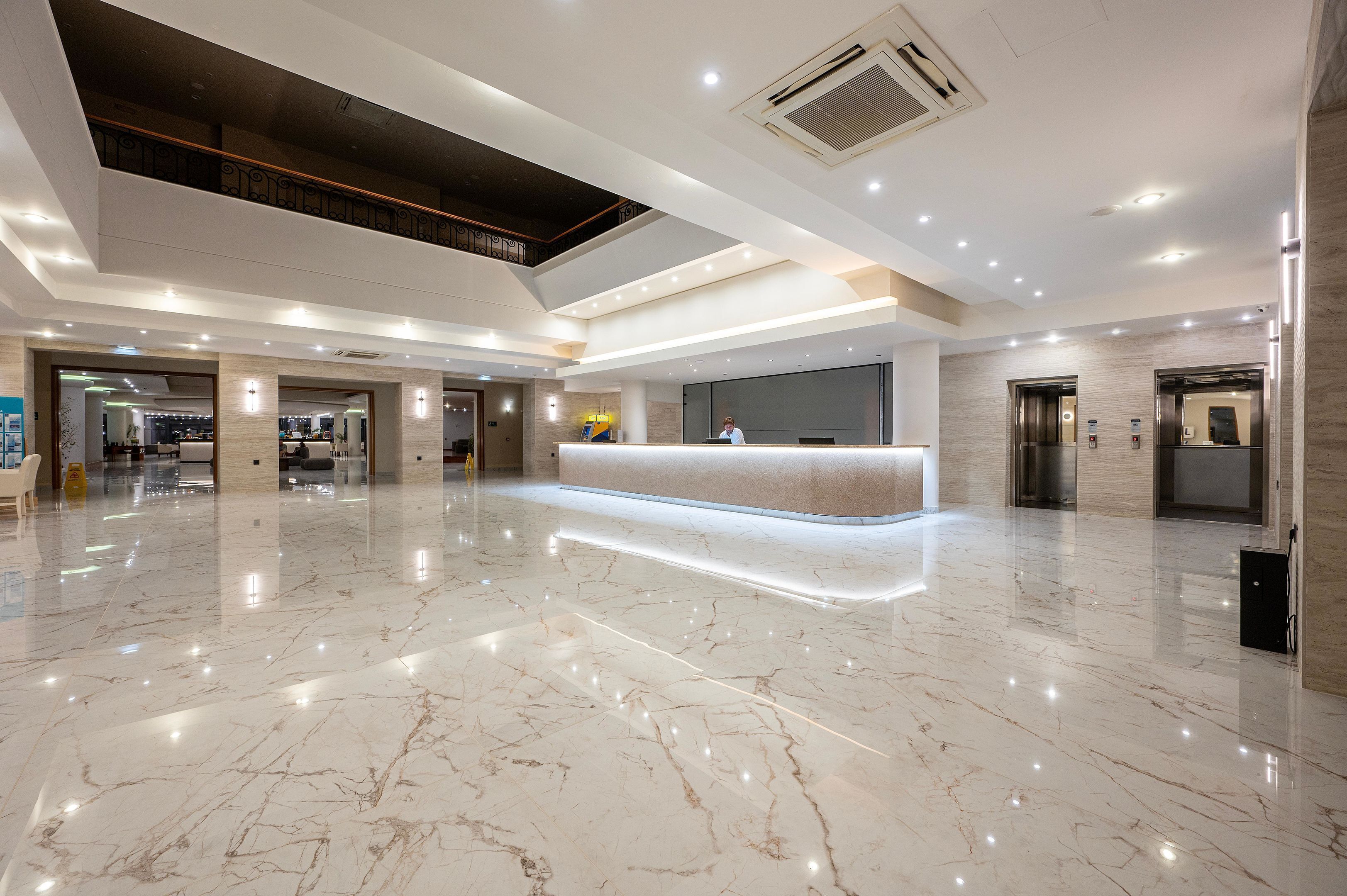 A spacious lobby with a marble floor, a reception desk, and a mezzanine level.
