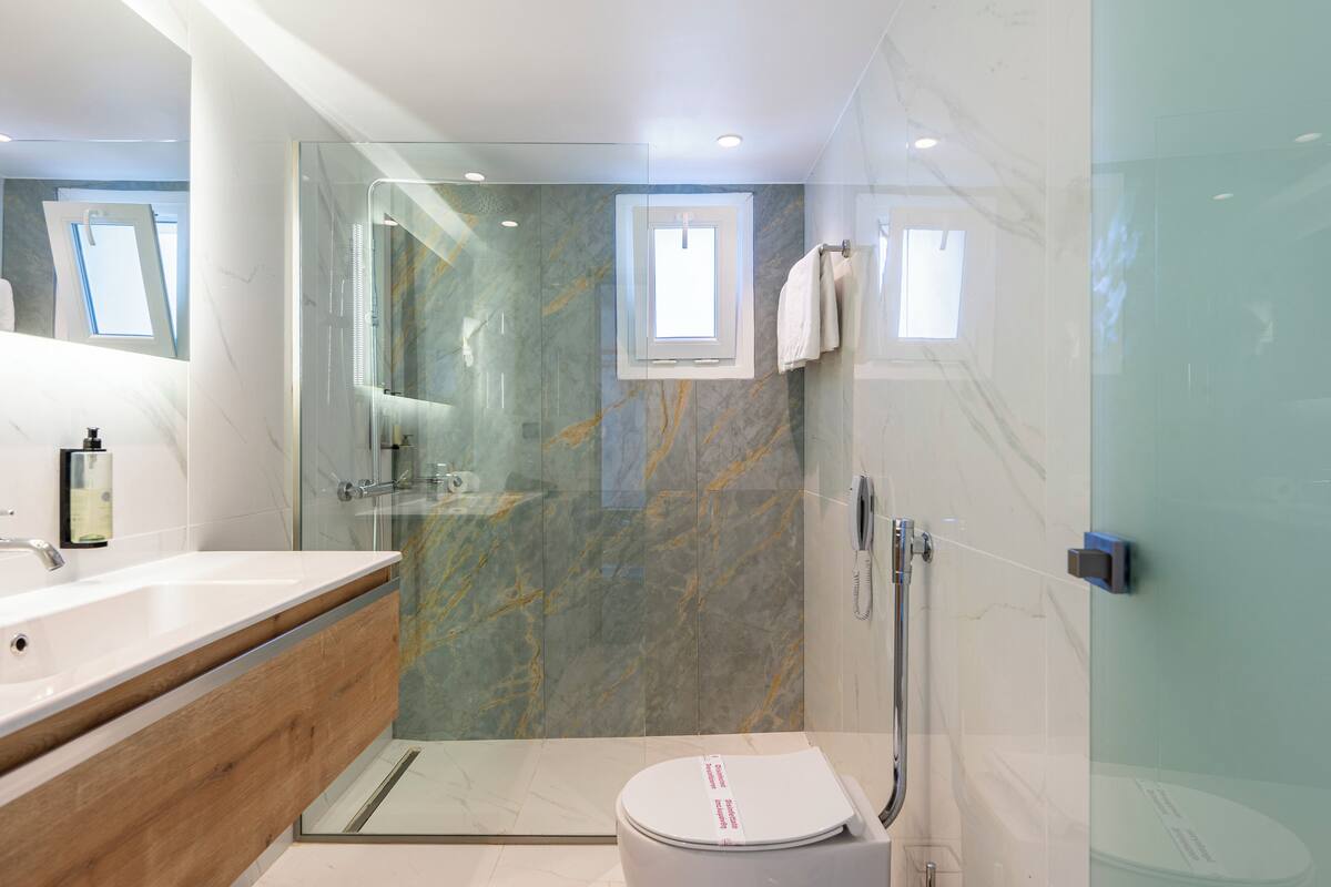 A modern bathroom with a glass-enclosed shower, a white sink, and a wooden vanity.