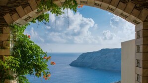 A stone archway overlooking a coastal view with a clear sky and distant cliffs. - Athina Palace Resort & Spa (Malevizi)