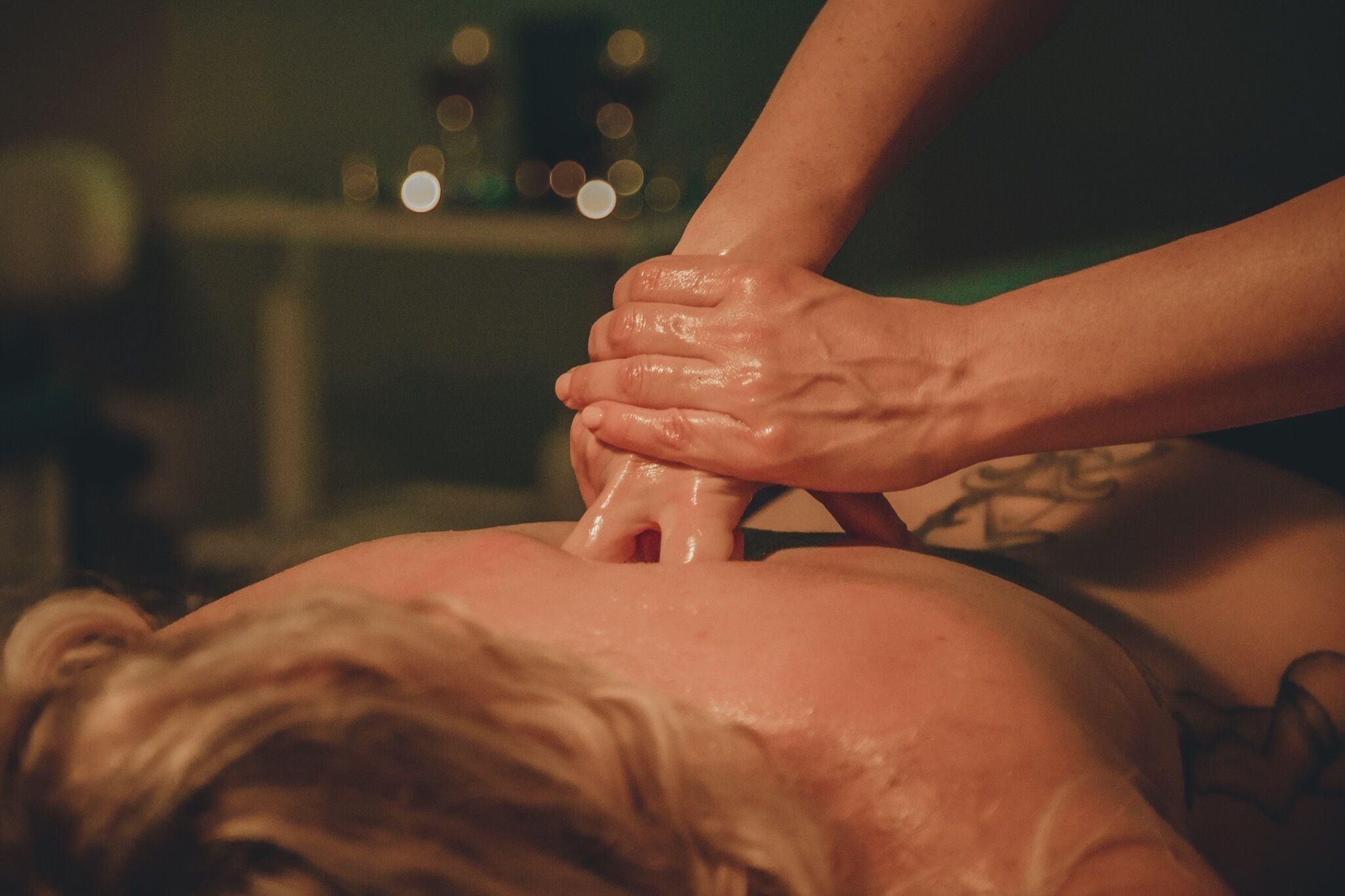 A close-up of hands performing a massage on a person's back.