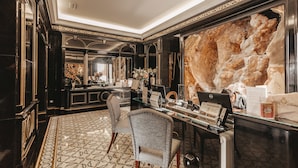 A luxurious lobby with a marble reception desk, a large stone wall, and a patterned floor. - Alentejo Marmoris Hotel & Spa, (Vila Vicosa)
