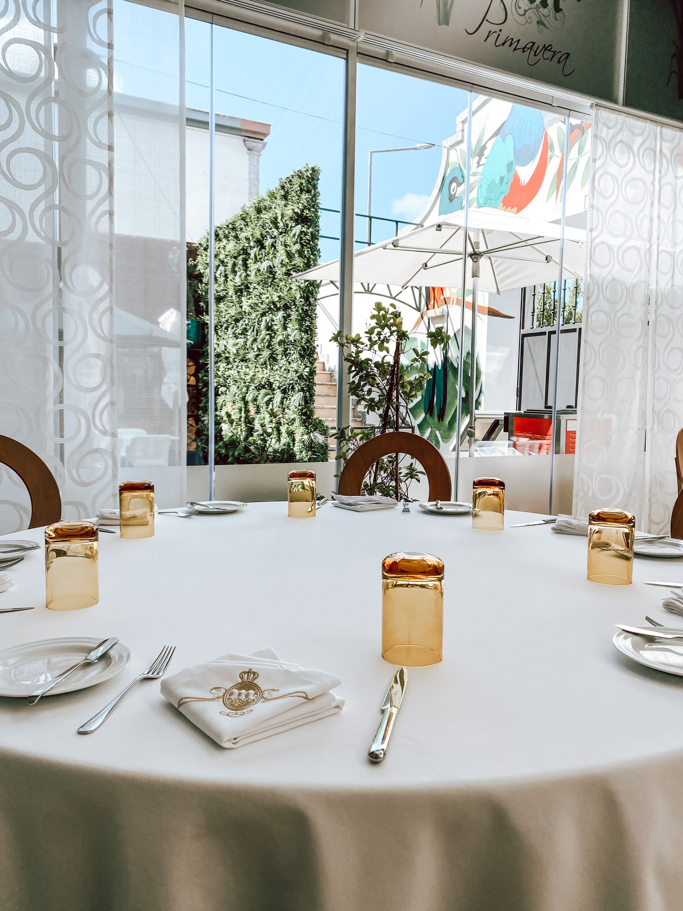 Une table à manger dressée pour six personnes, avec des chandeliers dorés, une nappe blanche et des couverts en argent.
