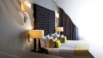 Un dormitorio moderno con cabecera capitonada, dos lámparas de noche, un televisor de pantalla plana y una variedad de almohadas.
