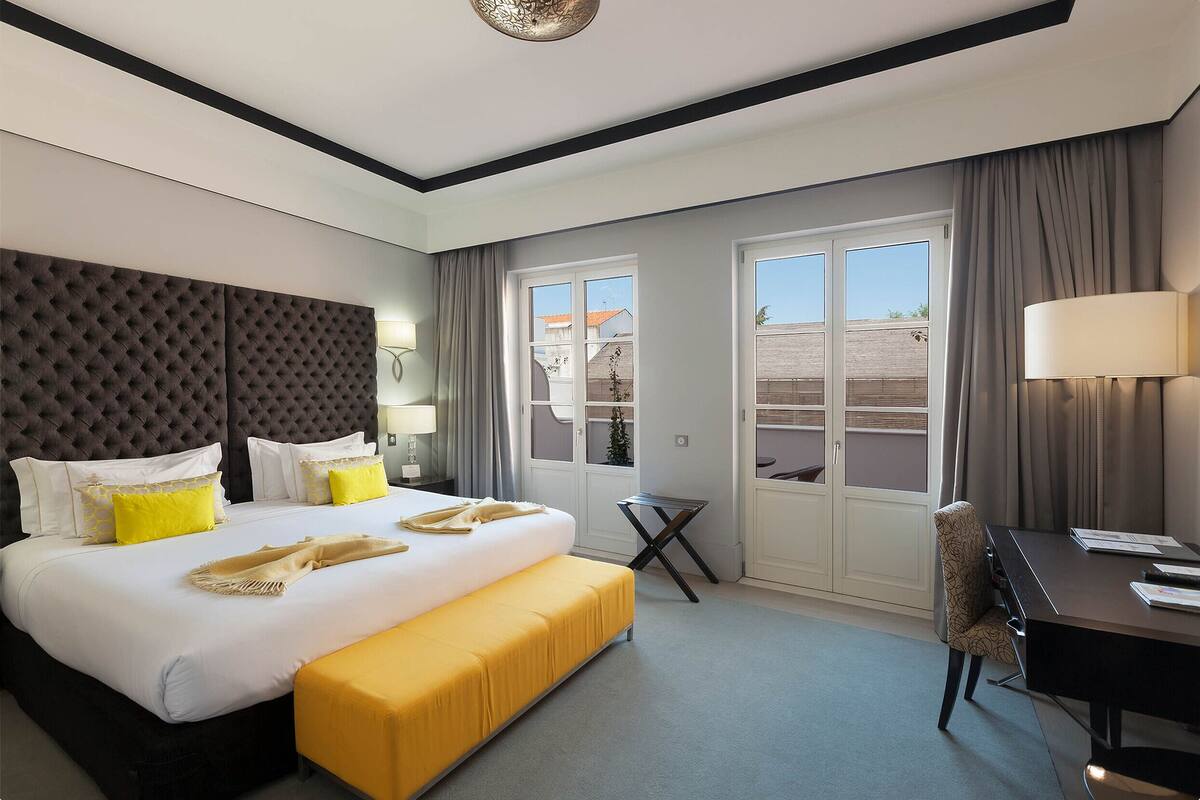 A hotel room with a large bed, a desk, and a view of the outside.