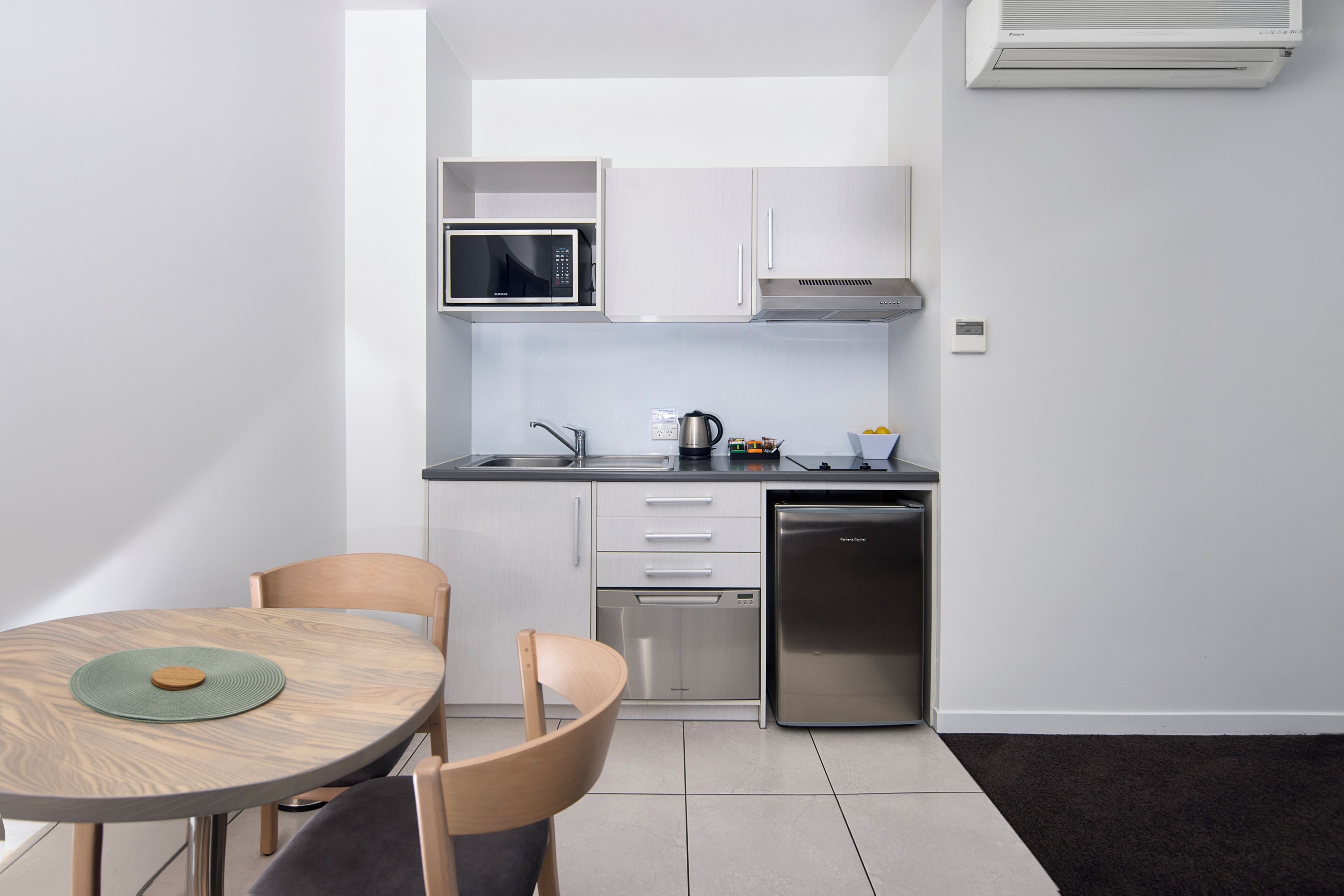 A compact kitchen with white cabinets, a microwave, a coffee maker, and a dishwasher.