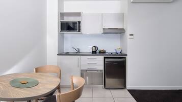 A compact kitchen with white cabinets, a microwave, a coffee maker, and a dishwasher.