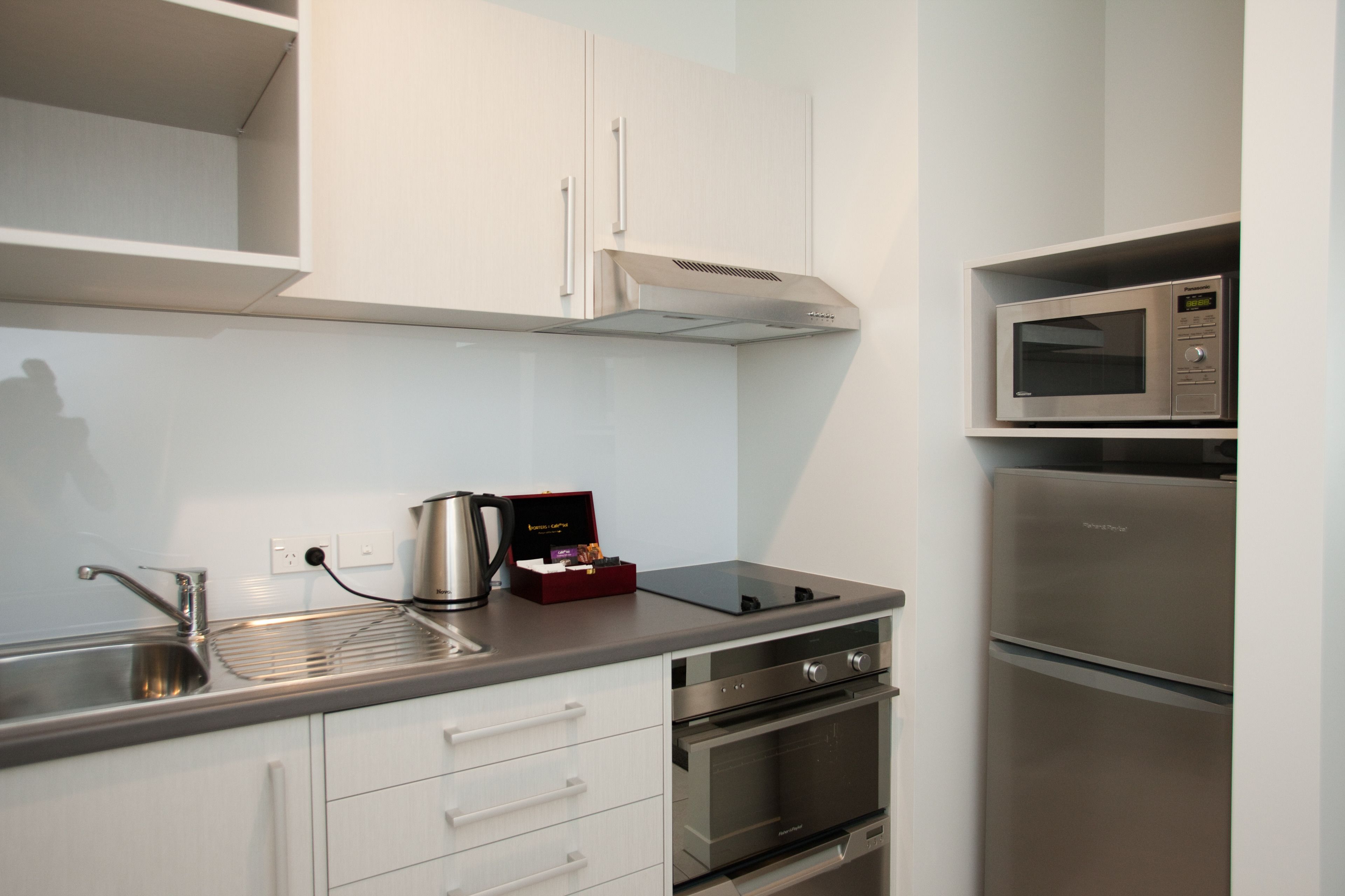 A modern kitchen with stainless steel appliances, white cabinetry, and a built-in microwave.