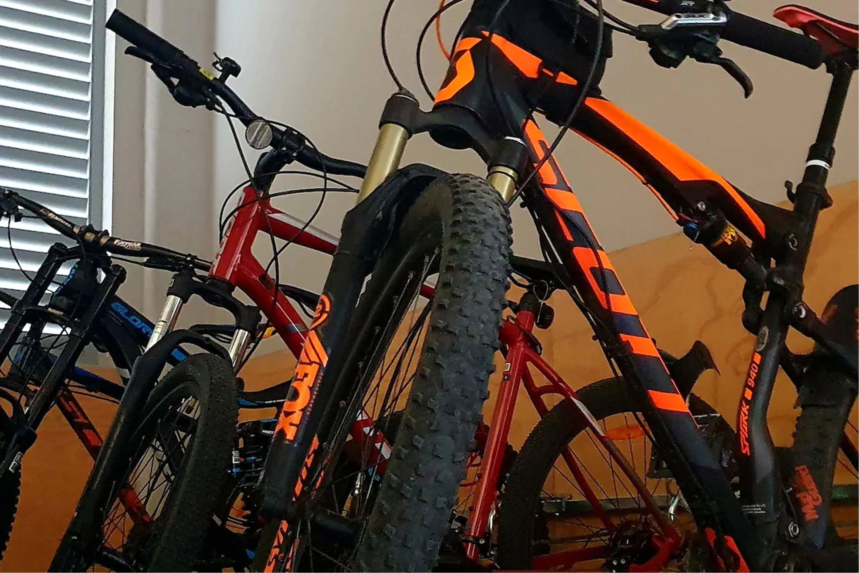 A close-up of a red mountain bike with black and orange accents, featuring a suspension fork and a textured tire.