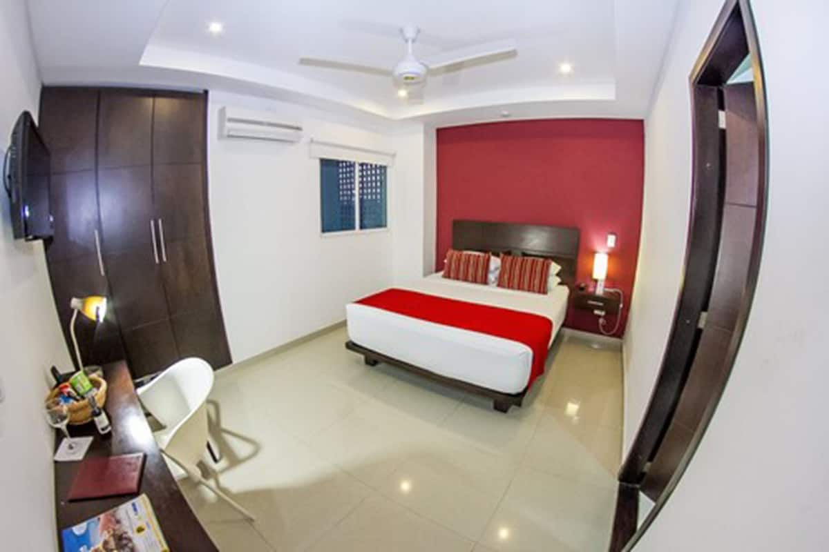 A modern bedroom with a bed, a desk, a chair, a wardrobe, and a television.