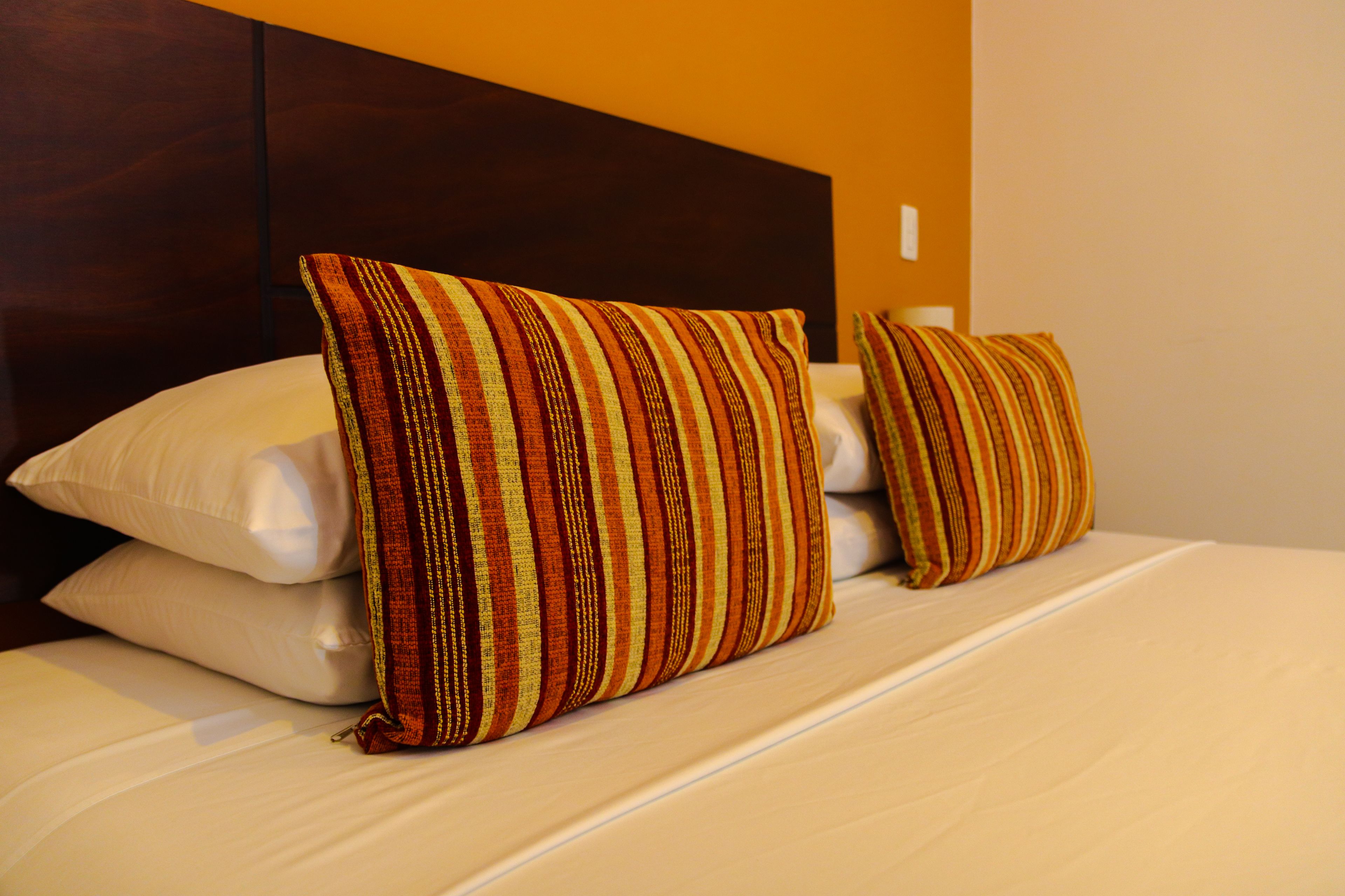 Uma cama com duas almofadas e cabeceira.