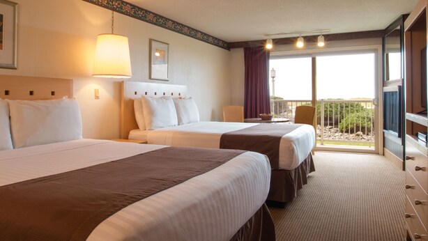 A hotel room with two beds, a large window with a view, and a balcony. - Hi-Tide Oceanfront Inn (Seaside)