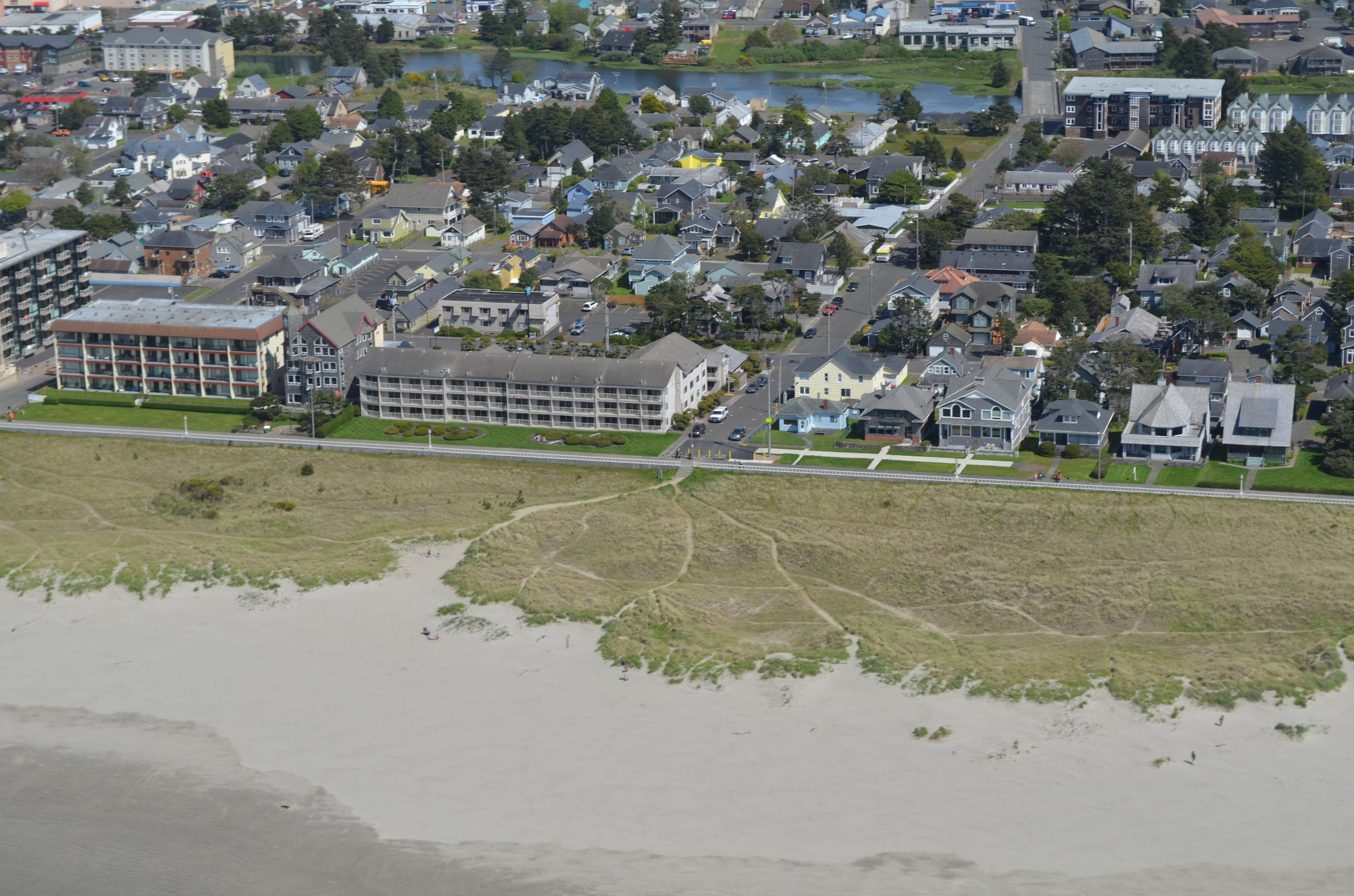 An aerial view of a residential area with houses, a road, and a body of water.