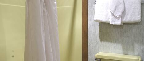 Un baño con cortina de ducha, inodoro y toallero.