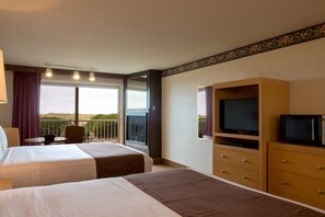 A hotel room with two beds, a television, a dresser, and a balcony with a view.