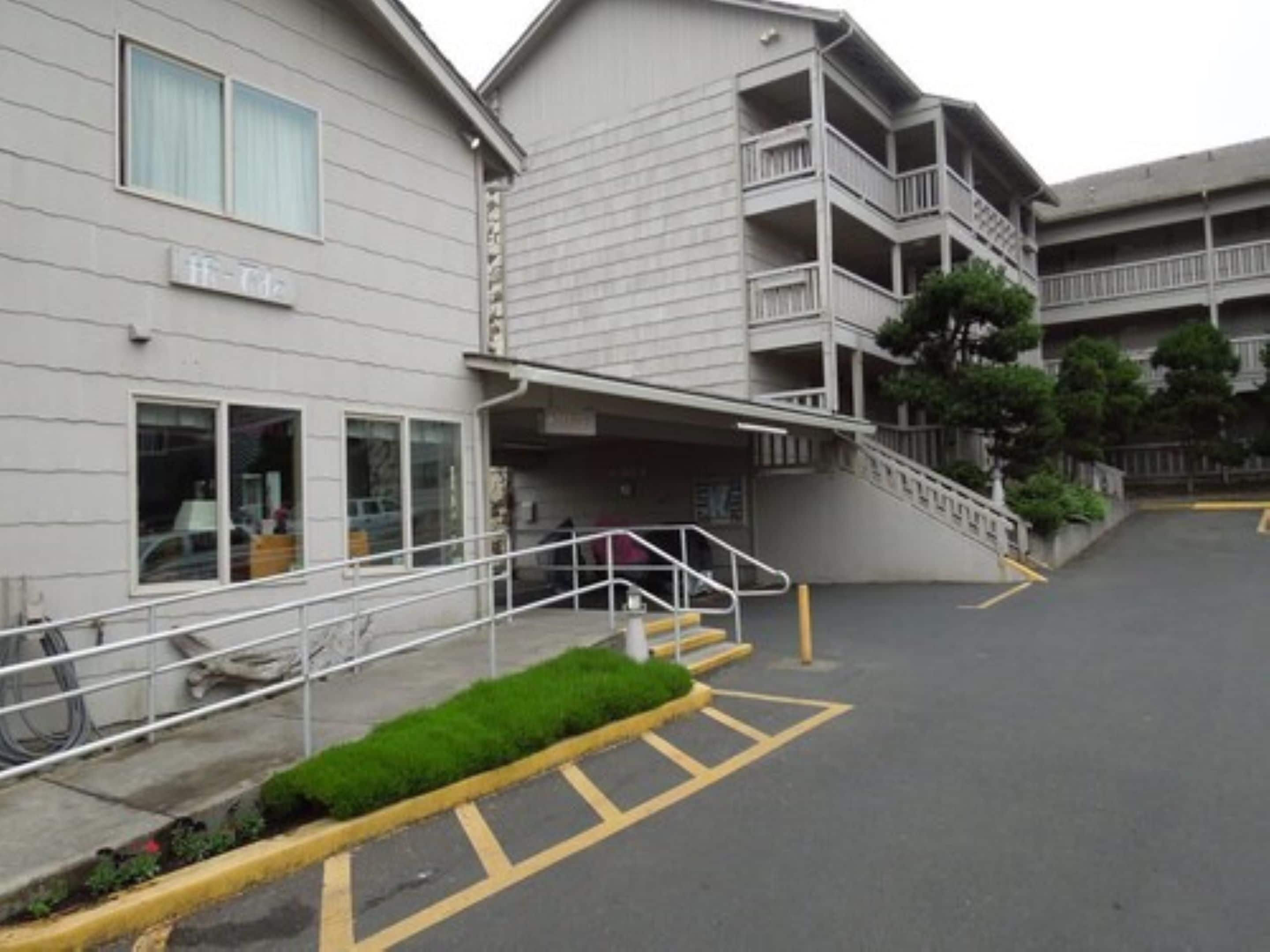 A multi-story building with a parking area in front.