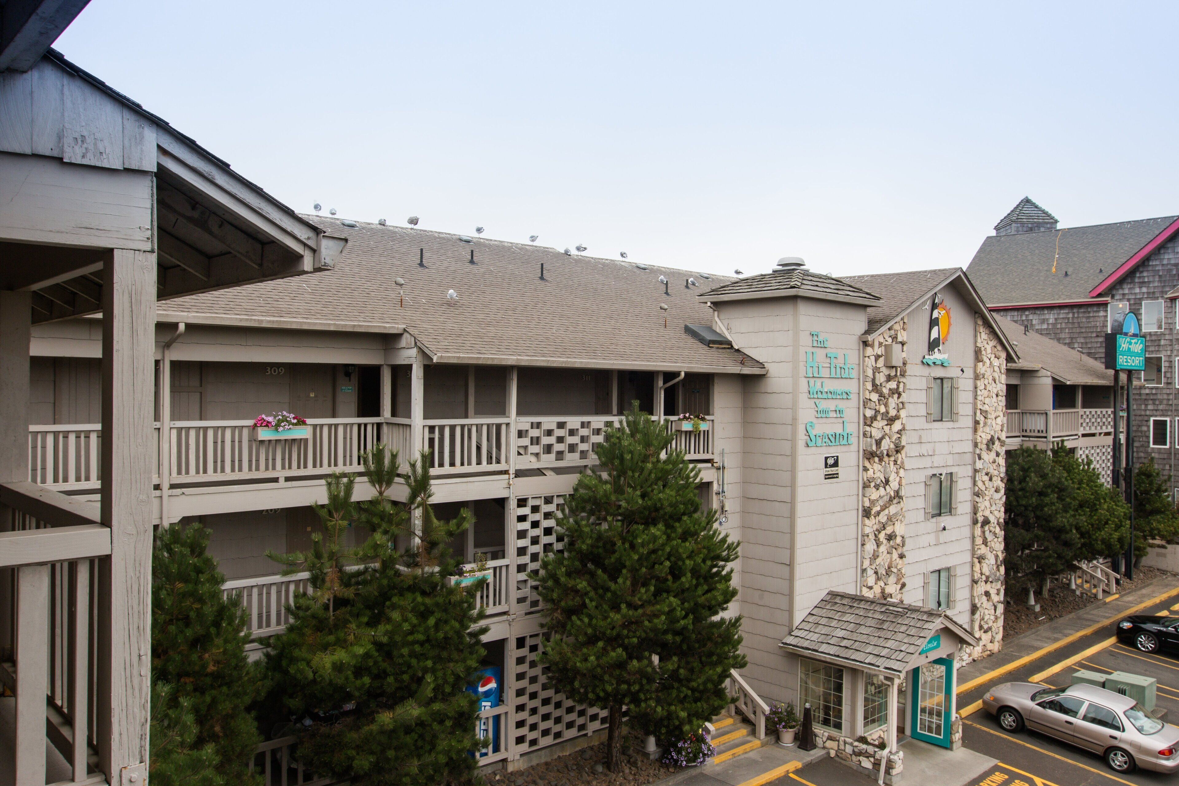 Un hôtel à plusieurs étages doté de balcons, d’une petite boutique et d’un espace de stationnement.