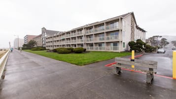 Un edificio de varios pisos con balcones, un paseo empedrado y una banca.