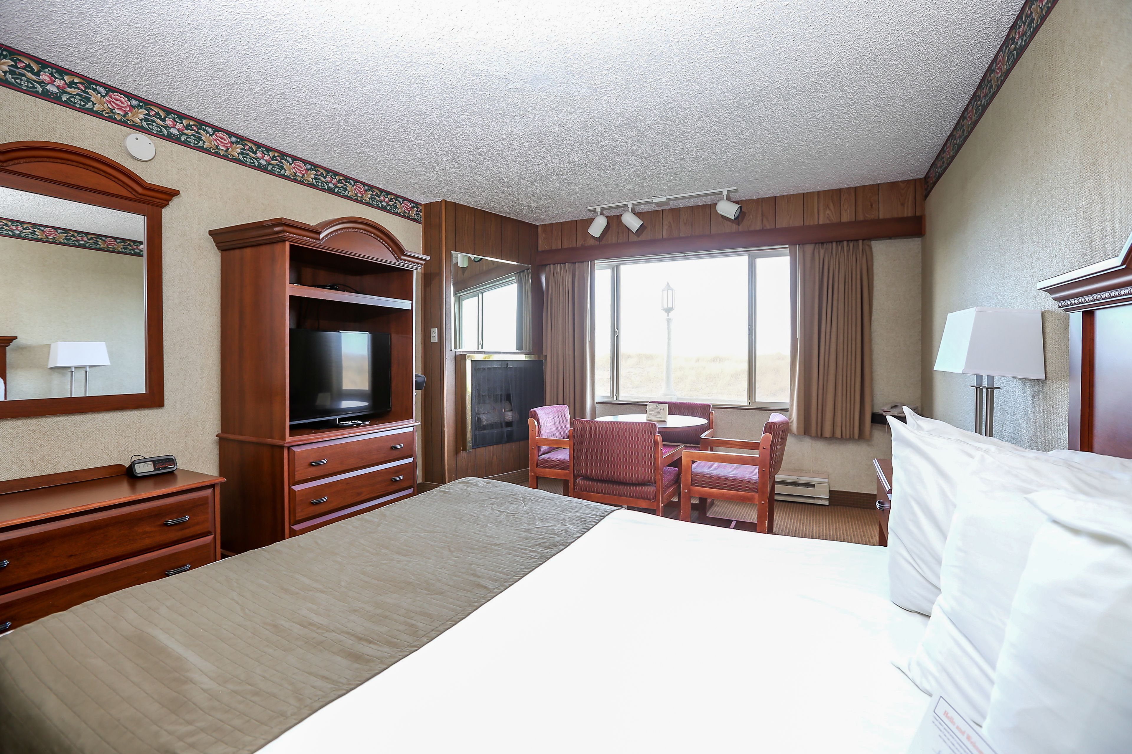 Habitación de hotel con una cama grande, televisión, escritorio con silla y ventana con cortinas.