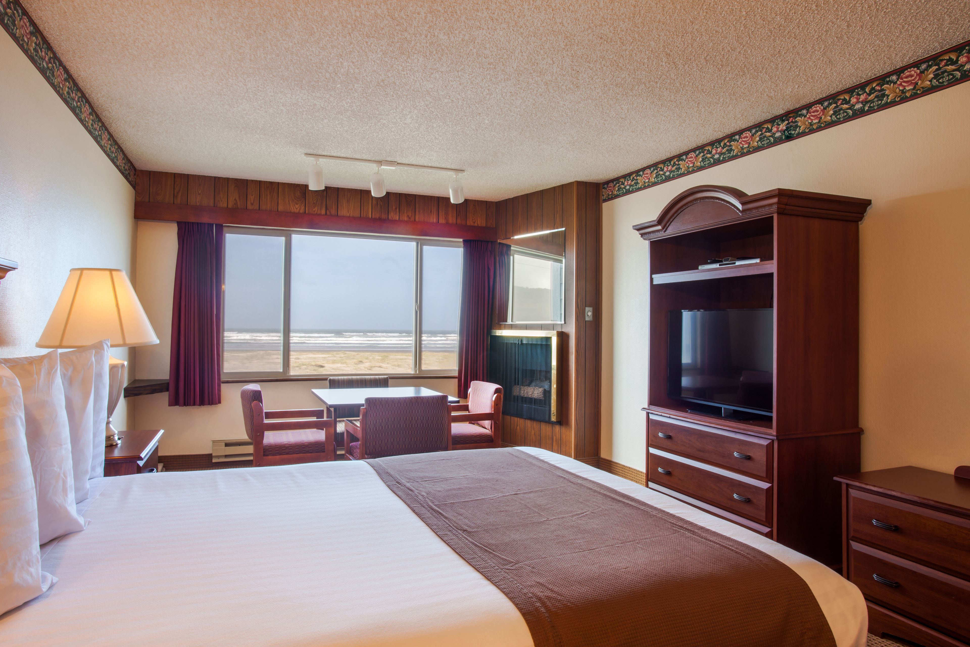 Una habitación de hotel con una cama grande, un escritorio con silla, televisión y vista a la playa.