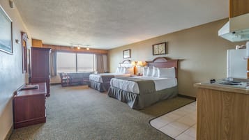 Habitación de hotel con dos camas, un escritorio, una silla y vistas al exterior.
