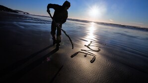 A silhouette of a person on a beach with the sun setting in the background.
