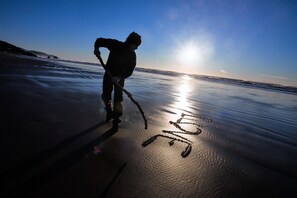A silhouette of a person on a beach with the sun setting in the background.