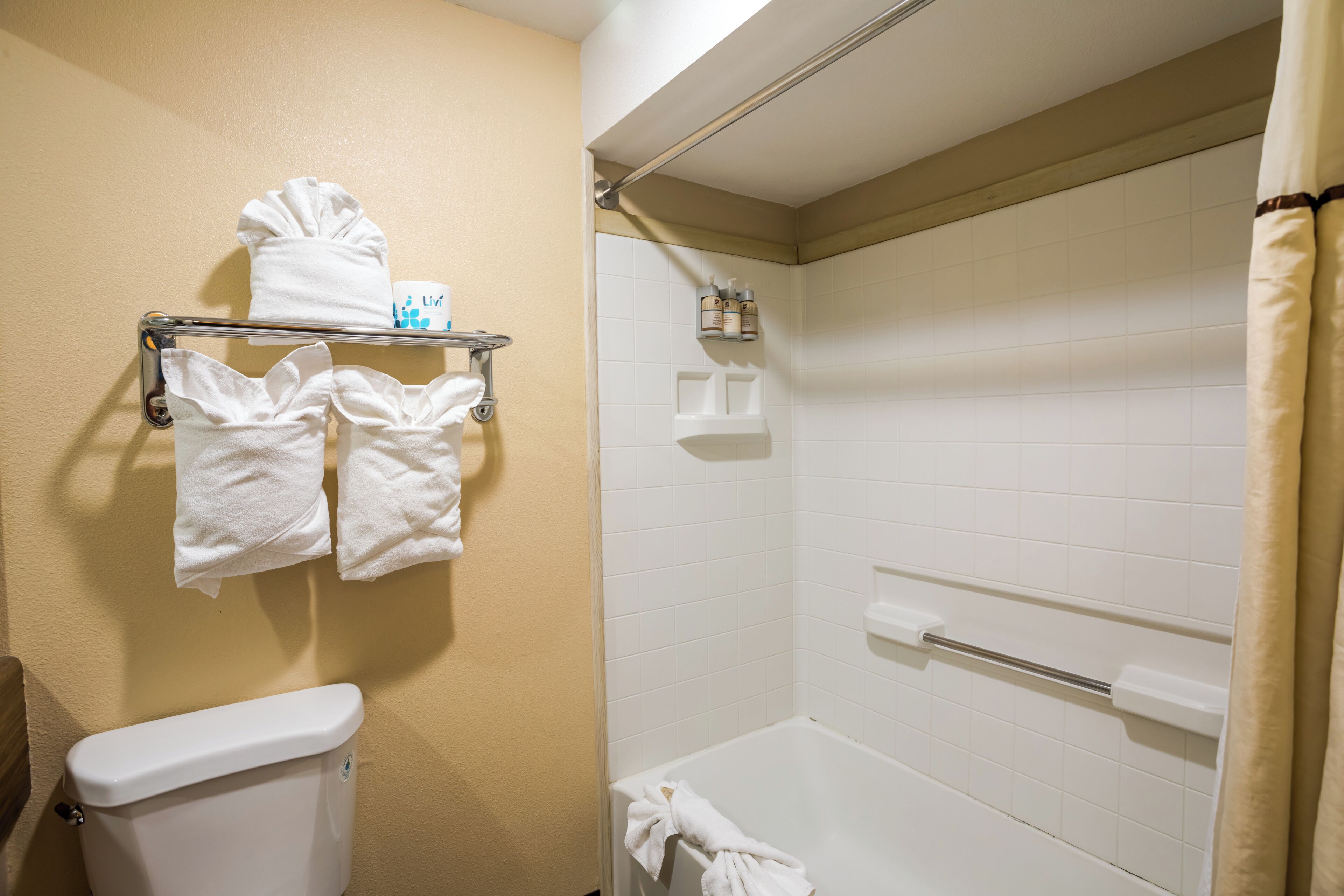 Un baño con inodoro, ducha y un perchero con toallas.
