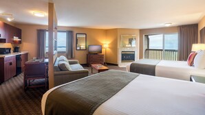 A hotel room with two beds, a desk, a chair, a television, and a view of the city. - Ebb Tide Oceanfront Inn (Seaside)