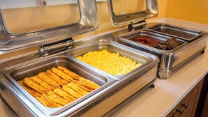 A buffet with various food items including scrambled eggs, bacon, and other meats.