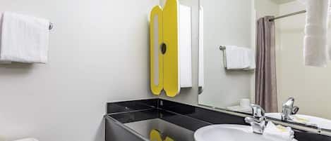 A bathroom with a white toilet, a black sink, a mirror, and a yellow towel rack.