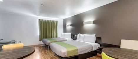 A hotel room with two beds, a dining table, and a yellow chair.