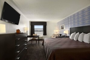 A hotel room with a bed, a desk, a chair, a television, and a window with a view. - Travelodge by Wyndham Hubbard OH (Hubbard)