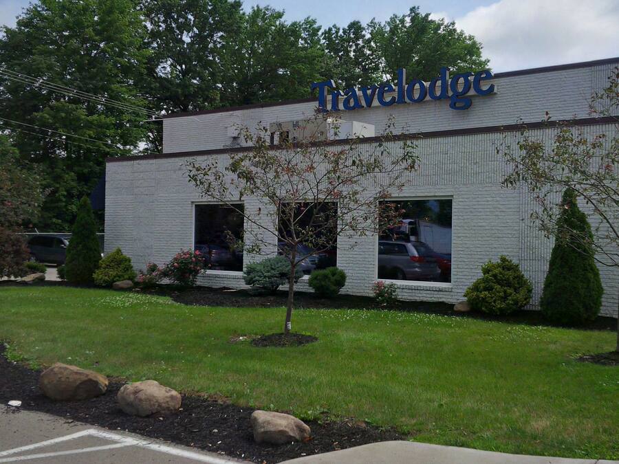 A Travelodge building with a brick facade, large windows, and a parking lot in front.