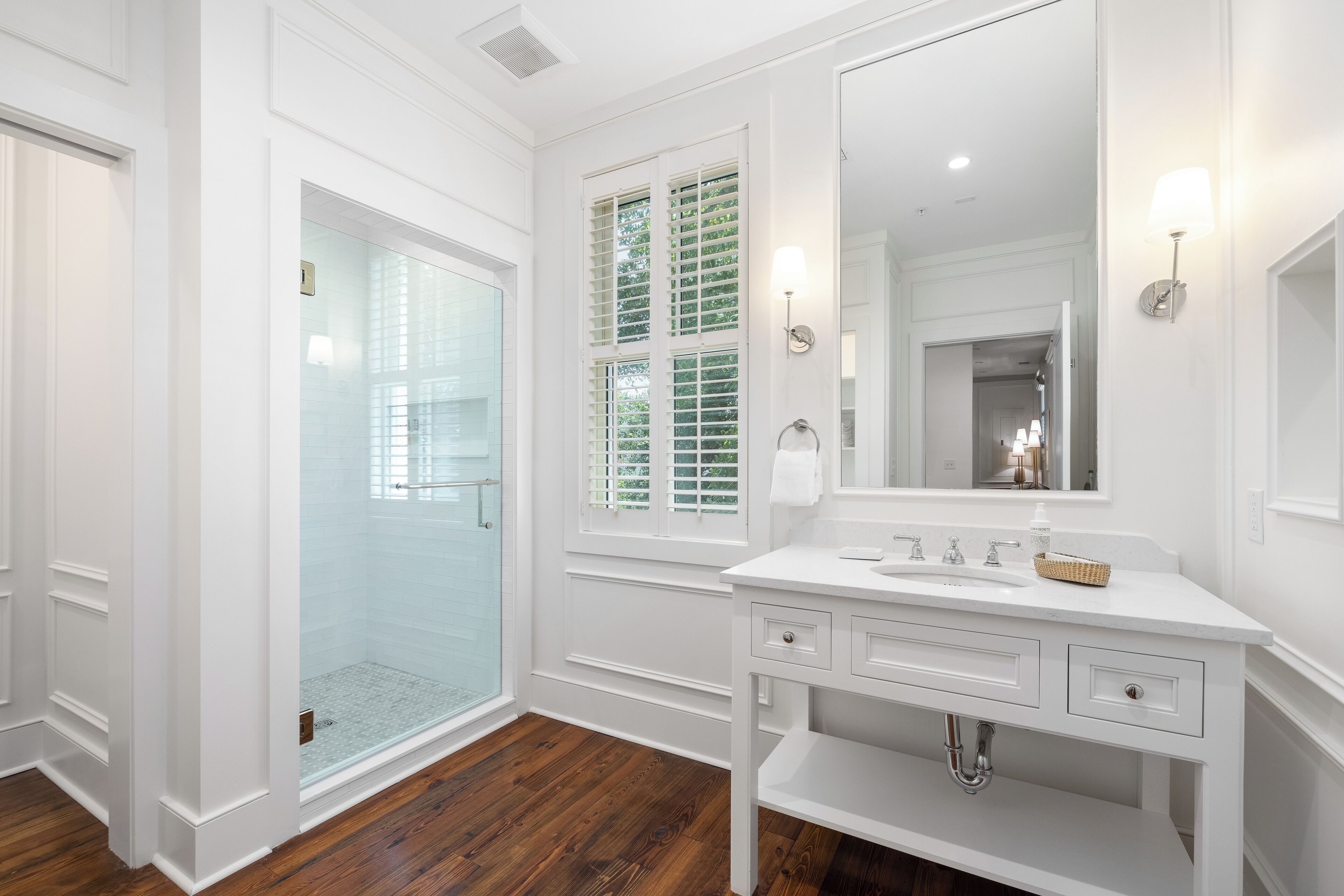 A modern bathroom with a glass shower, white vanity, and a large mirror.