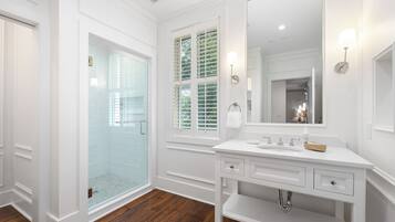 A modern bathroom with a glass shower, white vanity, and a large mirror.