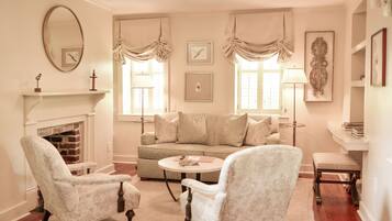A living room with a fireplace, a sofa, two armchairs, a coffee table, and a side table with a lamp.