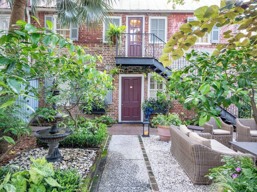 A courtyard with a brick building, a central door, a small fountain, and outdoor furniture.