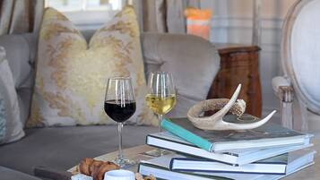 A cozy living room with a sofa, a table with books, a wine glass, and snacks.