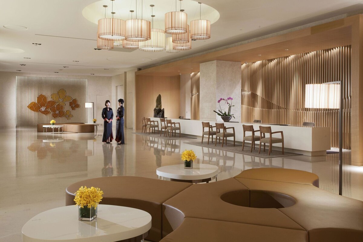 A modern hotel lobby with a reception desk, seating area, and decorative elements.