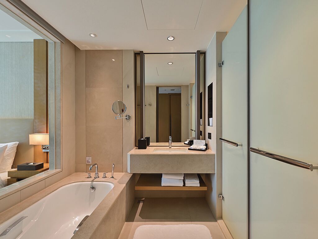 A modern bathroom with a bathtub, a vanity with a mirror, and a towel rack.