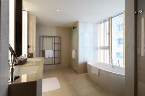 Un baño moderno con dos lavamanos, una bañera y una ducha.