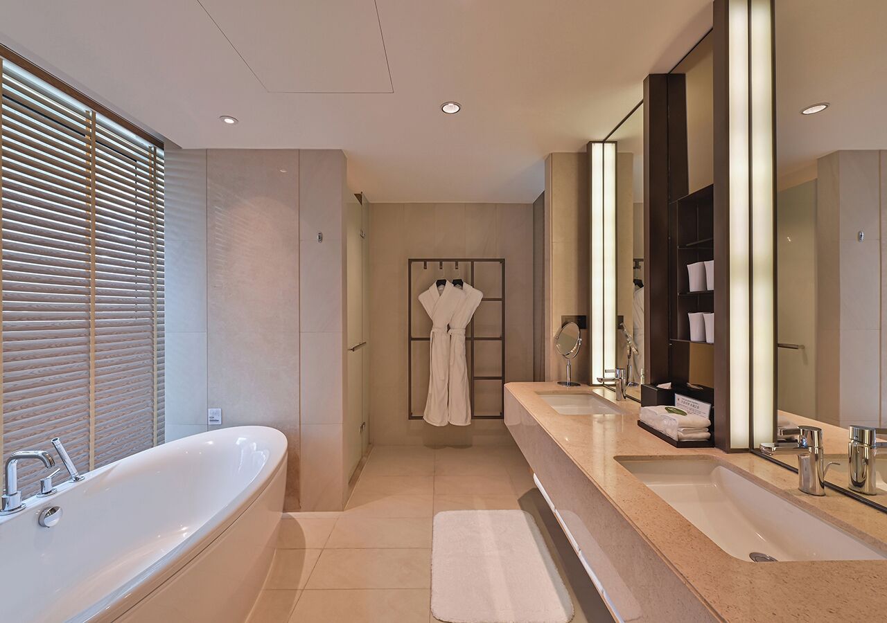 A modern bathroom with a large bathtub, two sinks, and a walk-in shower.