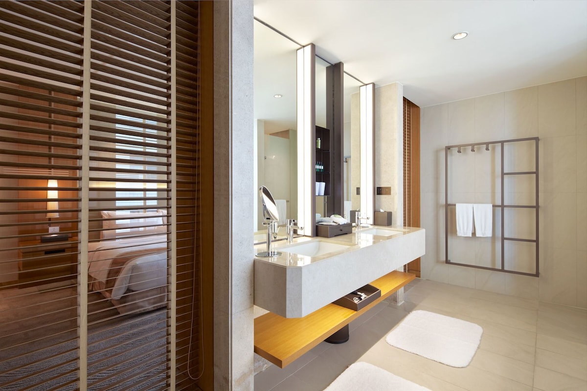 Un baño moderno con un espejo grande, dos lavamanos y un mueble de tocador de madera.